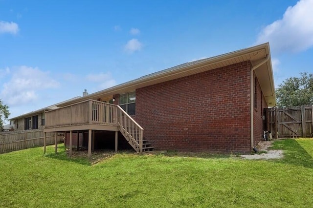 rear view of house with stairway, fence, a deck, a yard, and brick siding