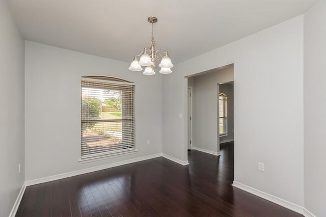 empty room featuring dark wood-style floors, baseboards, and a notable chandelier