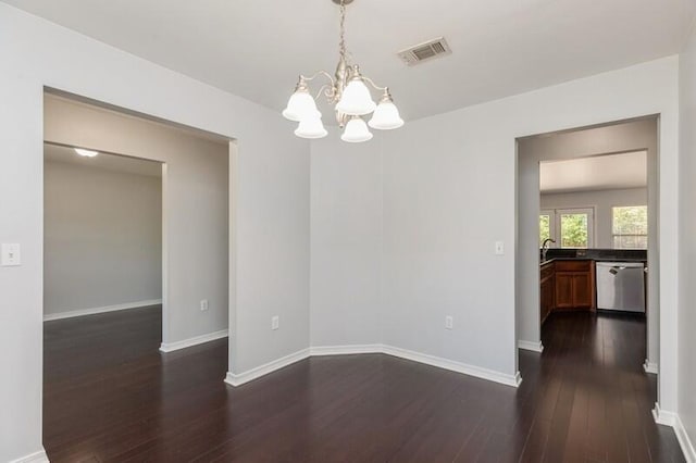 spare room with dark wood-style flooring, a notable chandelier, visible vents, a sink, and baseboards