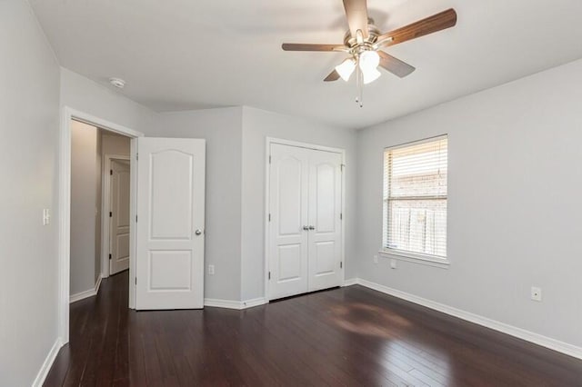 unfurnished bedroom featuring ceiling fan, a closet, baseboards, and dark wood-type flooring