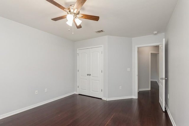 unfurnished bedroom with ceiling fan, dark wood-type flooring, visible vents, baseboards, and a closet