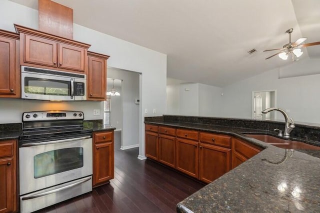 kitchen featuring stainless steel appliances, vaulted ceiling, dark wood-type flooring, sink, and dark stone countertops