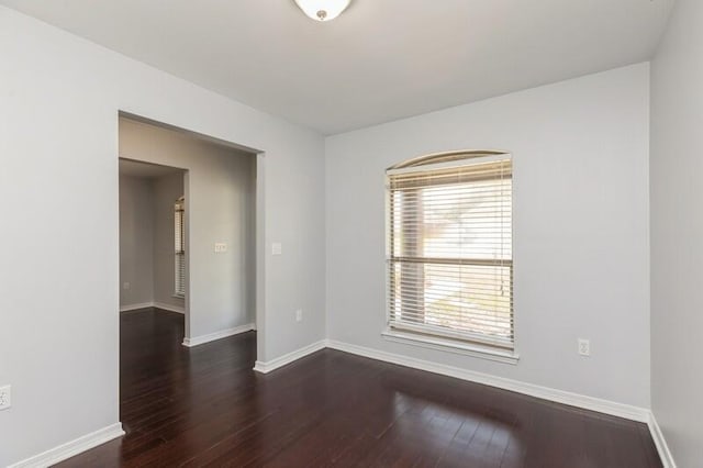 spare room with dark wood-style floors and baseboards