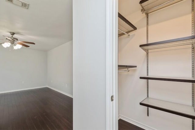 spacious closet featuring a ceiling fan, dark wood-style flooring, and visible vents