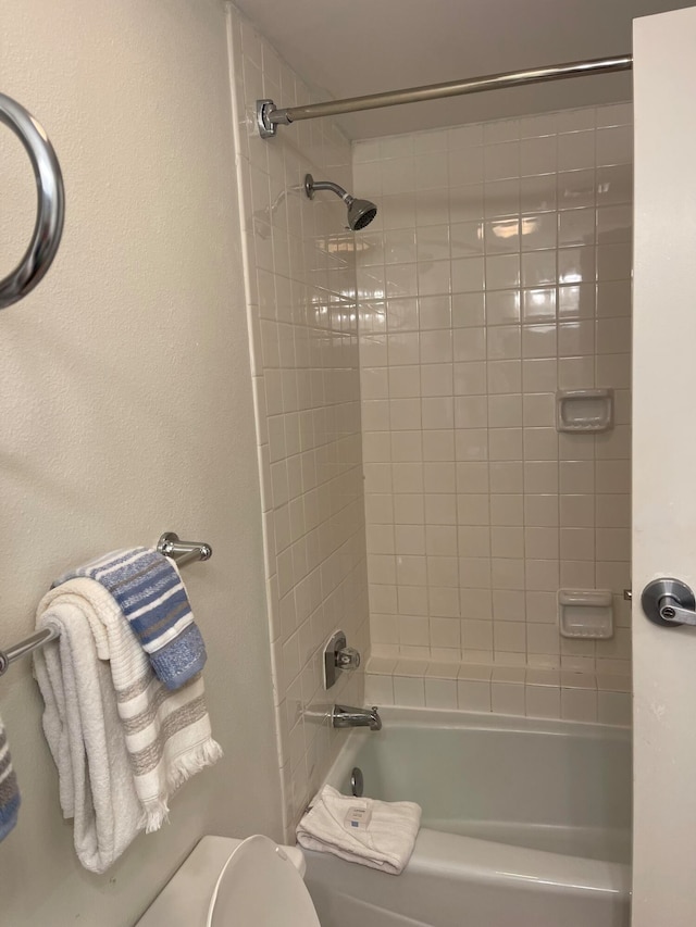 bathroom with tiled shower / bath combo and toilet