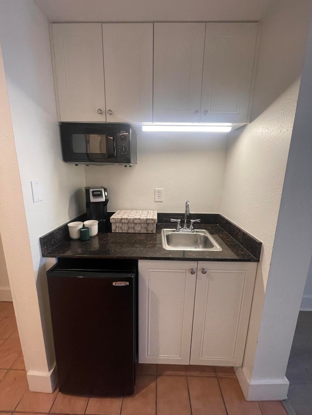 kitchen with white cabinetry, light tile patterned floors, black appliances, and sink