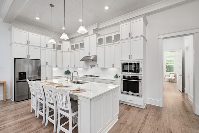 kitchen with appliances with stainless steel finishes, light hardwood / wood-style floors, a center island with sink, and sink