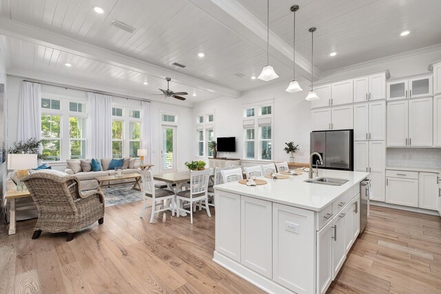 kitchen featuring backsplash, appliances with stainless steel finishes, beam ceiling, light hardwood / wood-style floors, and white cabinets