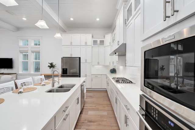 kitchen with sink, light wood-type flooring, appliances with stainless steel finishes, beamed ceiling, and white cabinetry