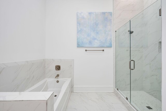 full bathroom with marble finish floor, a stall shower, a garden tub, and baseboards