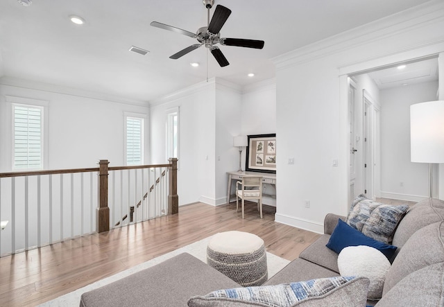 living area with visible vents, ornamental molding, wood finished floors, baseboards, and ceiling fan