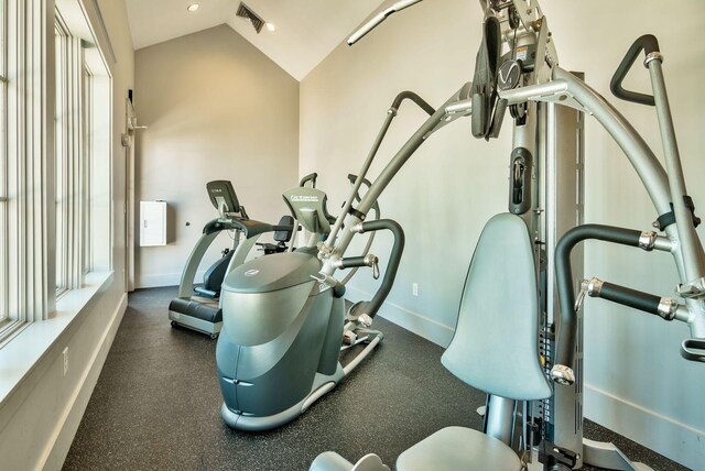 exercise room with visible vents, baseboards, and lofted ceiling