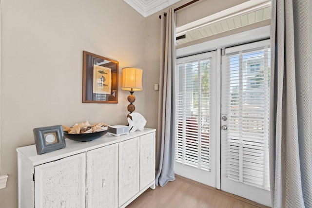 doorway featuring ornamental molding and light hardwood / wood-style floors