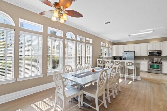 dining area featuring light hardwood / wood-style flooring, crown molding, and ceiling fan