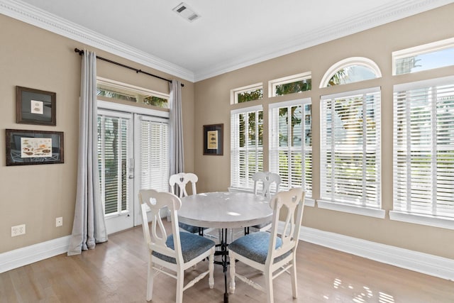 dining room featuring crown molding, a healthy amount of sunlight, and light hardwood / wood-style floors