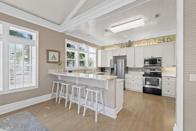 kitchen with light wood-type flooring, stainless steel appliances, kitchen peninsula, and white cabinetry