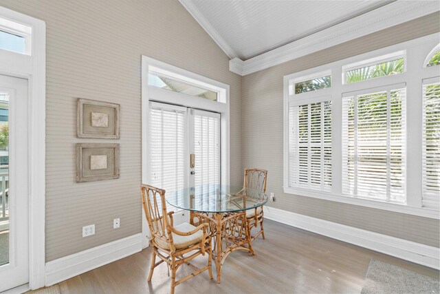 dining space with vaulted ceiling, ornamental molding, hardwood / wood-style floors, and french doors