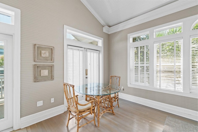 dining space with hardwood / wood-style flooring, a healthy amount of sunlight, lofted ceiling, and crown molding