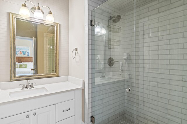 bathroom featuring a shower with shower door and vanity