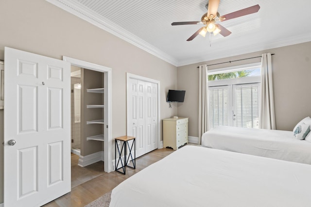 bedroom with light hardwood / wood-style flooring, crown molding, ceiling fan, and two closets