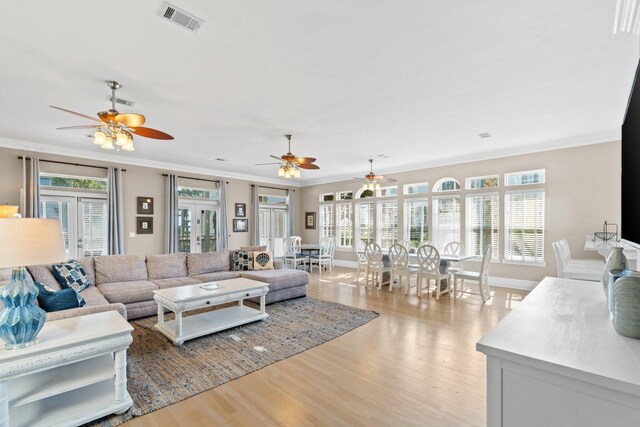 living room featuring crown molding, light hardwood / wood-style flooring, and a wealth of natural light