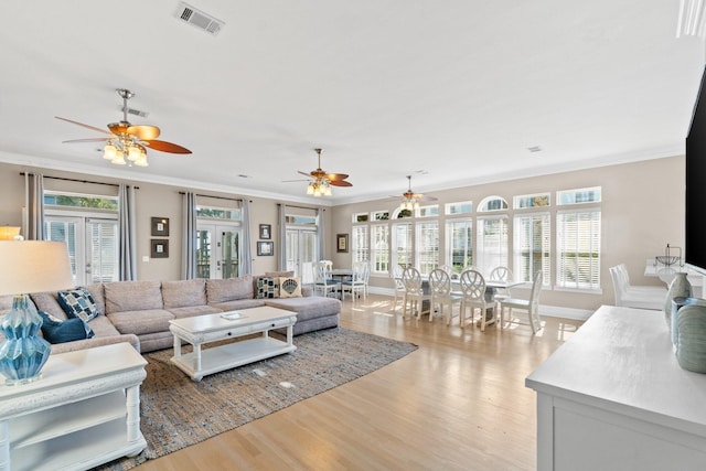 living room featuring french doors, ornamental molding, and light hardwood / wood-style flooring