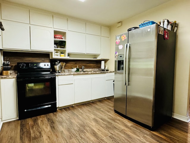 kitchen featuring light wood-type flooring, white cabinetry, black range with electric stovetop, stainless steel fridge, and sink