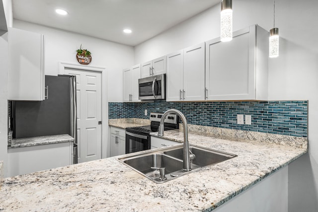 kitchen featuring stainless steel appliances, white cabinets, sink, backsplash, and decorative light fixtures