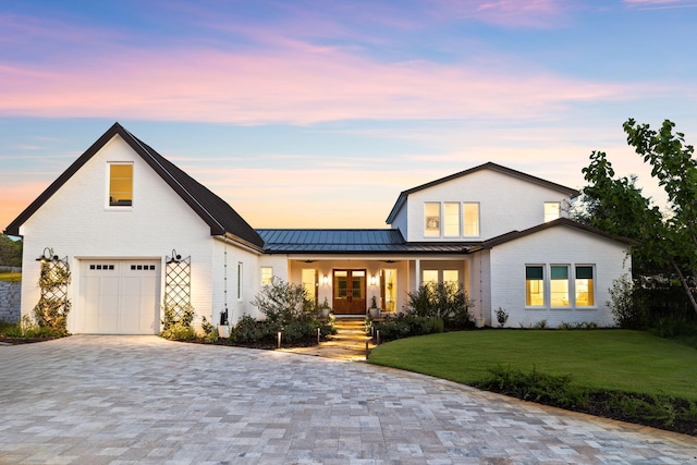 modern farmhouse featuring a garage and a yard