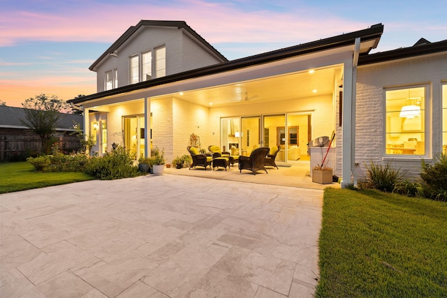 back house at dusk featuring a patio and a yard