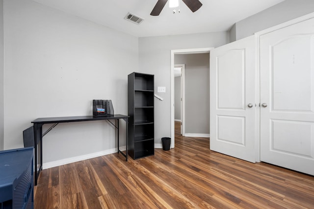 unfurnished office featuring a ceiling fan, visible vents, baseboards, and wood finished floors