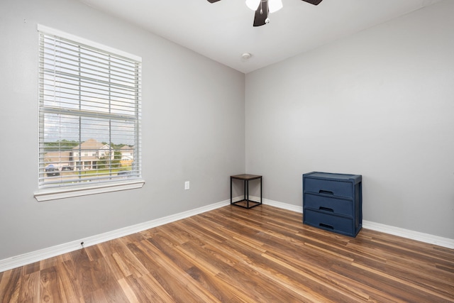 unfurnished room with wood finished floors, a ceiling fan, and baseboards