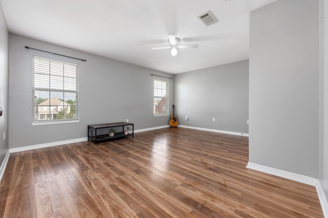 empty room featuring a healthy amount of sunlight, visible vents, baseboards, and wood finished floors