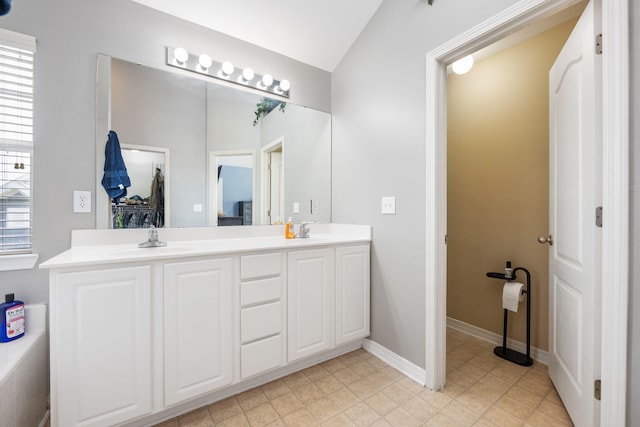 bathroom with double vanity, baseboards, a sink, and lofted ceiling