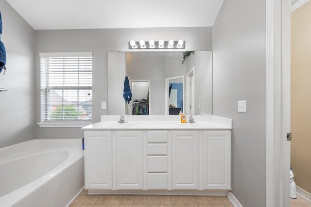 bathroom featuring a relaxing tiled tub, dual bowl vanity, and tile patterned flooring