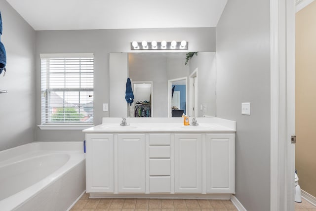 full bath with double vanity, a garden tub, toilet, and a sink