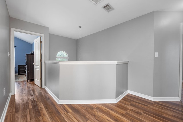 corridor featuring lofted ceiling, dark wood-type flooring, an upstairs landing, visible vents, and baseboards
