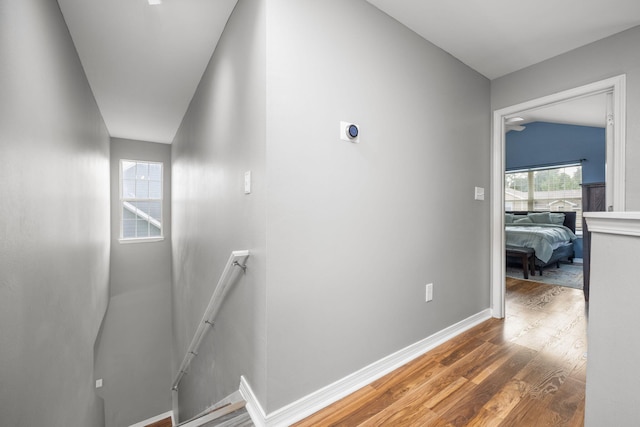 stairs featuring lofted ceiling, baseboards, and wood finished floors