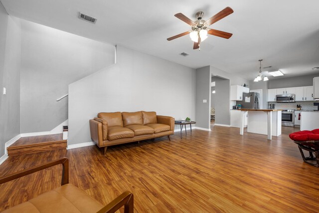 living area with visible vents, ceiling fan, stairway, and wood finished floors