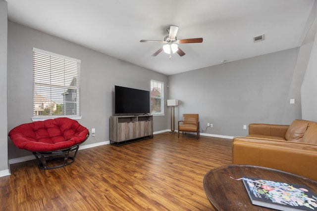 living area with a ceiling fan, visible vents, baseboards, and wood finished floors