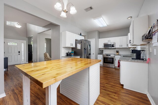 kitchen featuring decorative backsplash, dark hardwood / wood-style floors, white cabinetry, appliances with stainless steel finishes, and an inviting chandelier