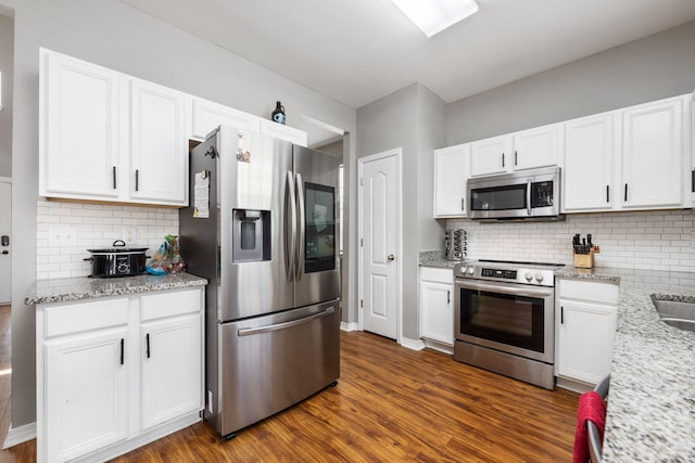 kitchen featuring stainless steel appliances, white cabinets, backsplash, light stone countertops, and dark wood finished floors