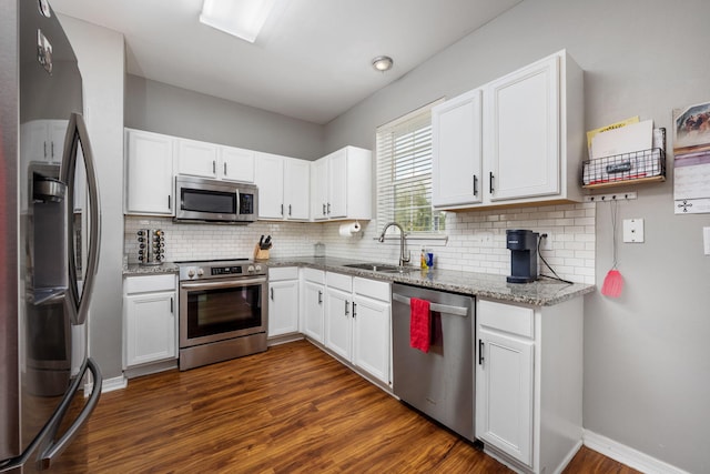 kitchen with stainless steel appliances, dark wood finished floors, a sink, and light stone counters