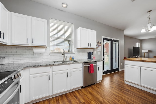 kitchen with dark wood finished floors, backsplash, appliances with stainless steel finishes, white cabinets, and a sink