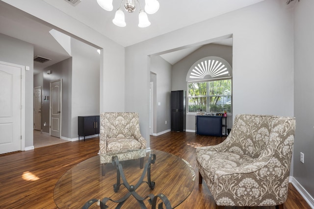 living area with a chandelier, wood finished floors, visible vents, baseboards, and vaulted ceiling