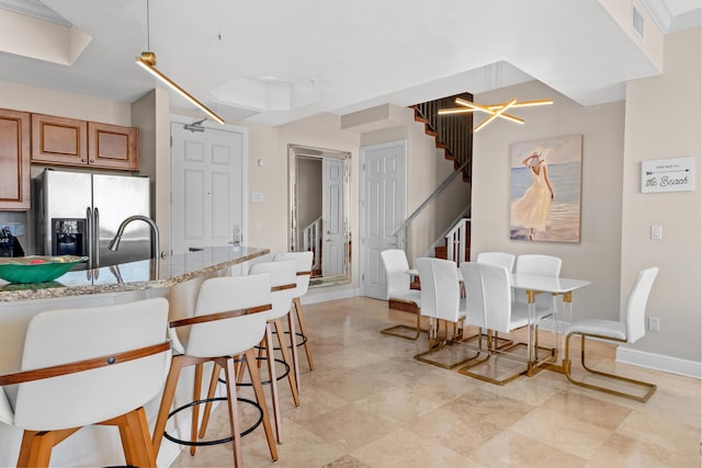 15100 Emerald Coast Pkwy Ph 2, Destin, FL 32541 - kitchen with light stone counters, brown cabinets, an inviting chandelier, a sink, and stainless steel fridge