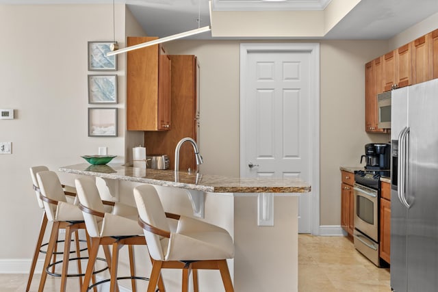 15100 Emerald Coast Pkwy Ph 2, Destin, FL 32541 - kitchen with light stone counters, a breakfast bar area, a peninsula, baseboards, and appliances with stainless steel finishes
