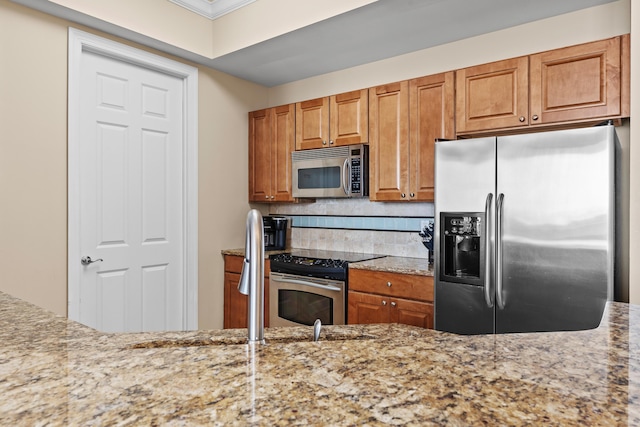 15100 Emerald Coast Pkwy Ph 2, Destin, FL 32541 - kitchen featuring brown cabinetry, light stone counters, stainless steel appliances, and backsplash