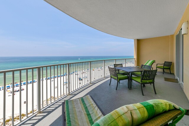 balcony with a water view and a view of the beach