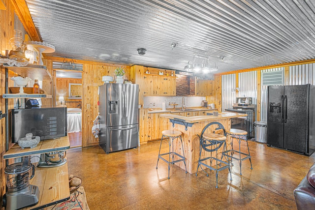 kitchen featuring black fridge with ice dispenser, tasteful backsplash, range, sink, and stainless steel fridge